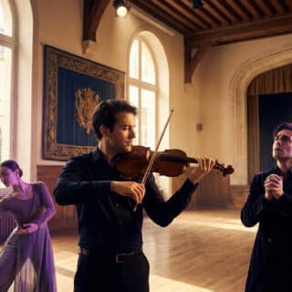 Un violoniste, un chanteur et une danseuse interprètent une œuvre dans une salle de répétition historique du conservatoire.