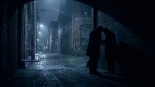 Deux silhouettes discutent dans une ruelle sombre avec des lignes de connexion numériques reliant les bâtiments.