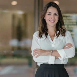 Femme professionnelle souriante, bras croisés, dans un bureau