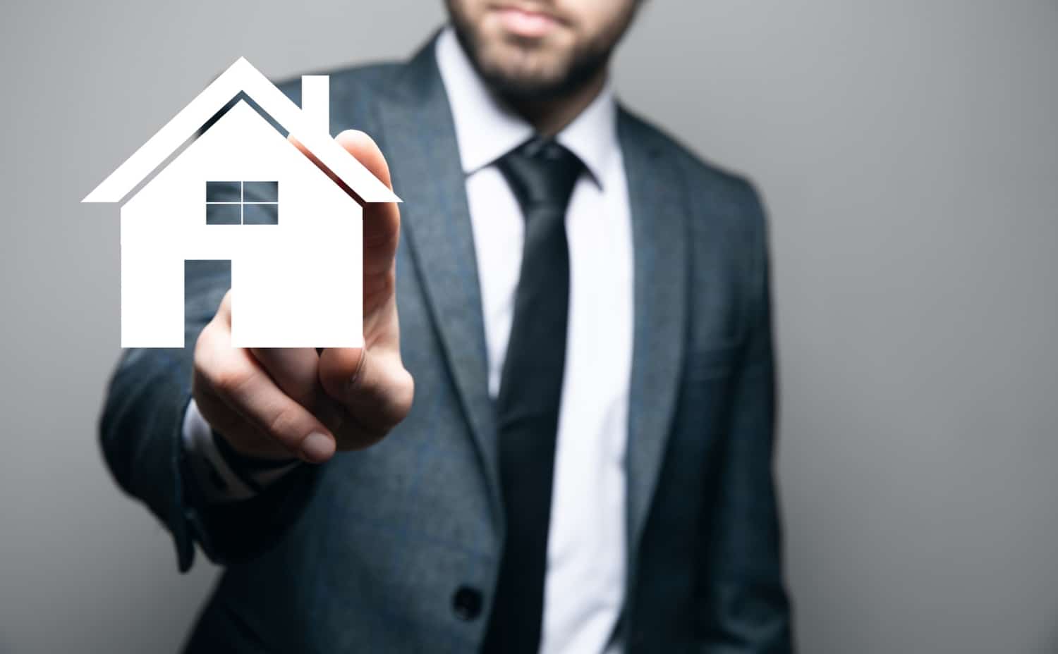 Un professionnel en costume clique sur une maison virtuelle illustrant le concept d'expertise en immobilier