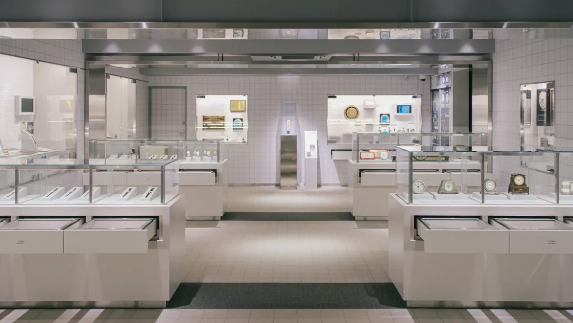 Vitrines en verre présentant des montres et des horloges, de part et d’autre d’une allée centrale