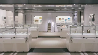 Vitrines en verre présentant des montres et des horloges, de part et d’autre d’une allée centrale
