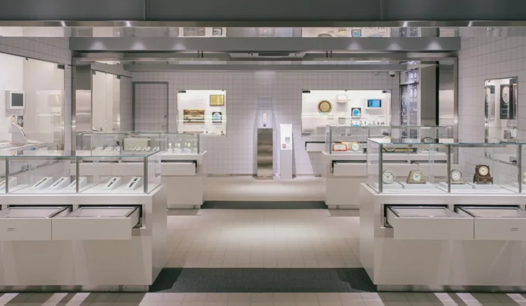 Vitrines en verre présentant des montres et des horloges, de part et d’autre d’une allée centrale
